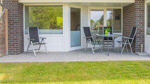Un porche cubierto con una mesa y cuatro sillas, una planta en maceta y vistas al exterior.