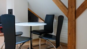 A dining area with a round table and four black chairs, wooden beams on the ceiling, and a white wall. - Spatzennest by Interhome (Spiez)