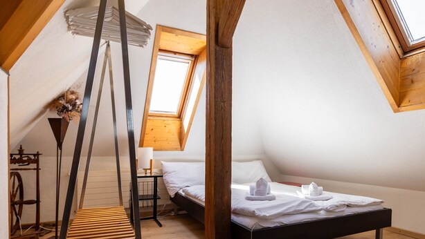 A bedroom with a sloped ceiling, a bed, a small table, and a lamp. - Spatzennest by Interhome (Spiez)