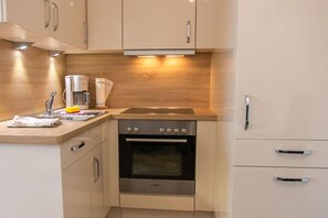 Eine kompakte Küche mit Backofen von Bosch, einer Kaffeemaschine und einem Spülbecken.