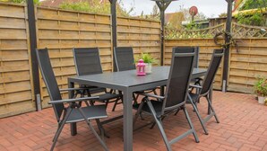 A patio with a table and chairs, surrounded by a wooden fence and brick flooring. - Kleine Perle - Waldstraße - "Relaxation and recreation in the little pearl on (Dahme)