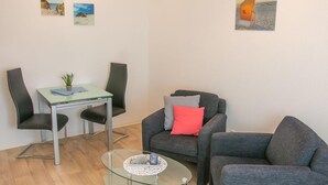 A living room with a glass table, two chairs, a sofa, and two paintings on the wall. - Kleine Perle - Waldstraße - "Relaxation and recreation in the little pearl on (Dahme)