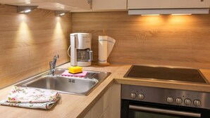 A modern kitchen with a stainless steel sink, a coffee maker, and a built-in oven. - Kleine Perle - Waldstraße - "Relaxation and recreation in the little pearl on (Dahme)