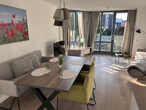 Una sala de estar moderna con comedor, un sofá, una mesa de centro y un ventanal con cortinas.