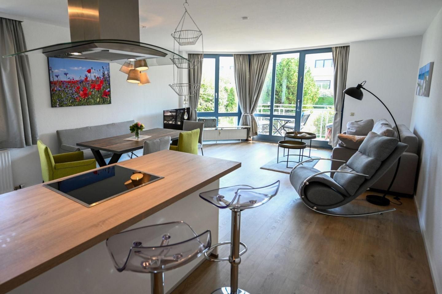 A modern living space with a dining area, a sofa, a rocking chair, and a large window.