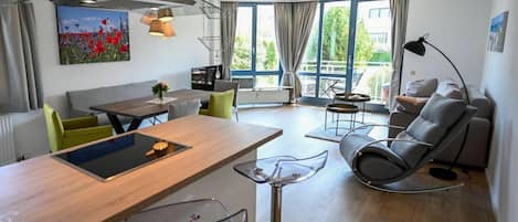 A modern living space with a dining area, a sofa, a rocking chair, and a large window.
