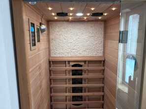 Ein schmaler Raum mit Holzwänden, einer Wand im Ziegelsteinmuster und einer Decke mit eingelassenen Leuchten.