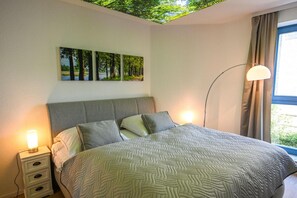 Ein Schlafzimmer mit Bett, Nachttischlampen, einer Stehlampe und einem Fenster mit Vorhängen.