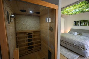 A room with a bed, a wooden cabinet, a brick wall, and a ceiling with a skylight.