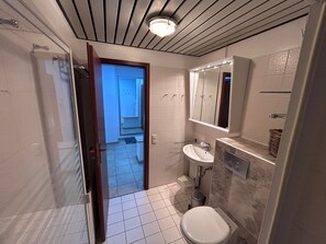 Ein Badezimmer mit Dusche, Waschbecken und Toilette.