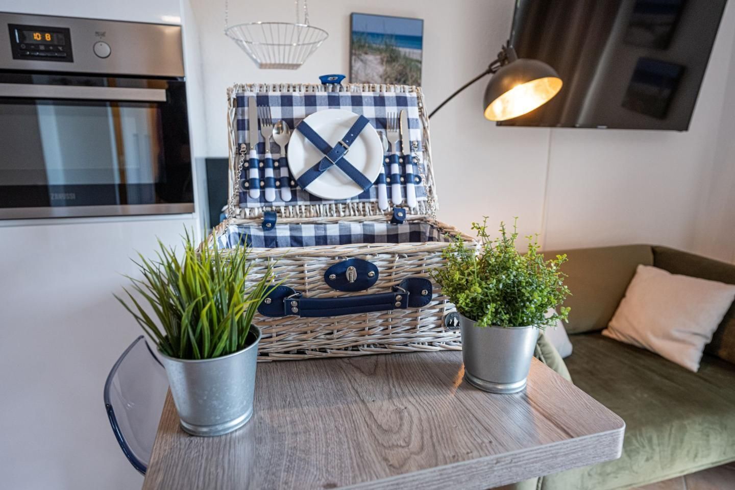 A kitchen with a checkered cloth basket, two potted plants, and a modern oven.