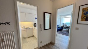 A modern apartment with a kitchen, a living area with a view, and a dining area. - Beach hotel - 56 - sea view and beach chair included! (Dahme)