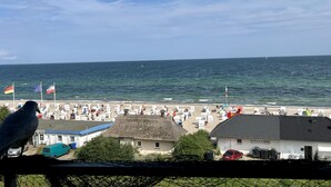 A coastal view with a beach, flags, and buildings. - Beach hotel - 56 - sea view and beach chair included! (Dahme)