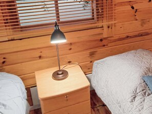 Habitación con literas de madera, una mesita de noche y una lámpara.