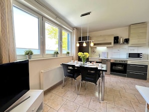 A modern kitchen with a dining area, large windows, and a built-in oven.