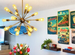 A modern interior with a unique light fixture, wall art, and a vase of tulips. - Wake to Waves, Watch Rockets Soar: Your Dreamy Oceanfront Condo Awaits (Cocoa Beach)