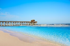 Eine hölzerne Pier, die sich ins Meer erstreckt, mit einer kleinen Konstruktion am Ende.