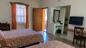 A hotel room with two beds, a desk, a chair, a TV, and a bathroom.
