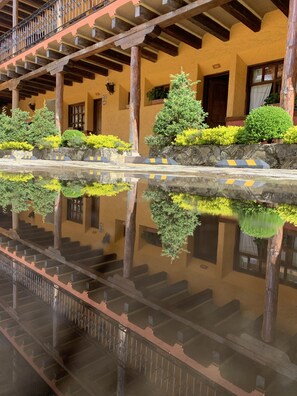 A hotel with a reflective pool, wooden balconies, and a stone wall with greenery.
