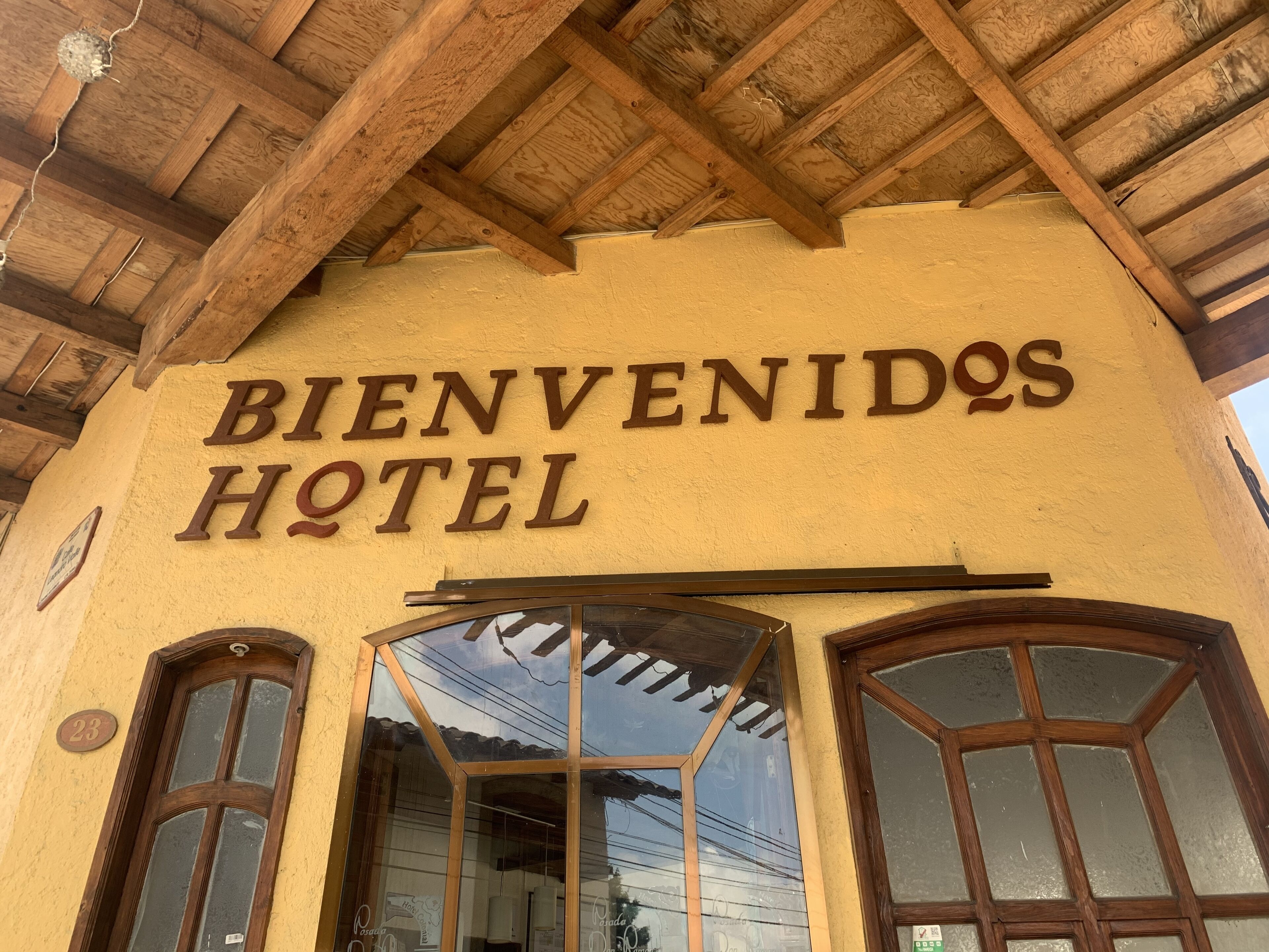A hotel entrance with a wooden ceiling and a sign that reads "BIENVENIDOS HOTEL".
