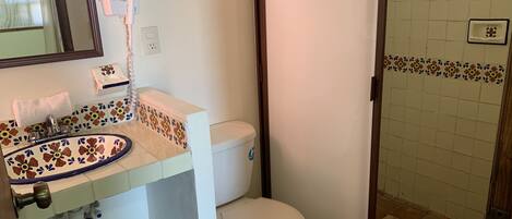 Un baño con inodoro, lavamanos y zona de ducha.