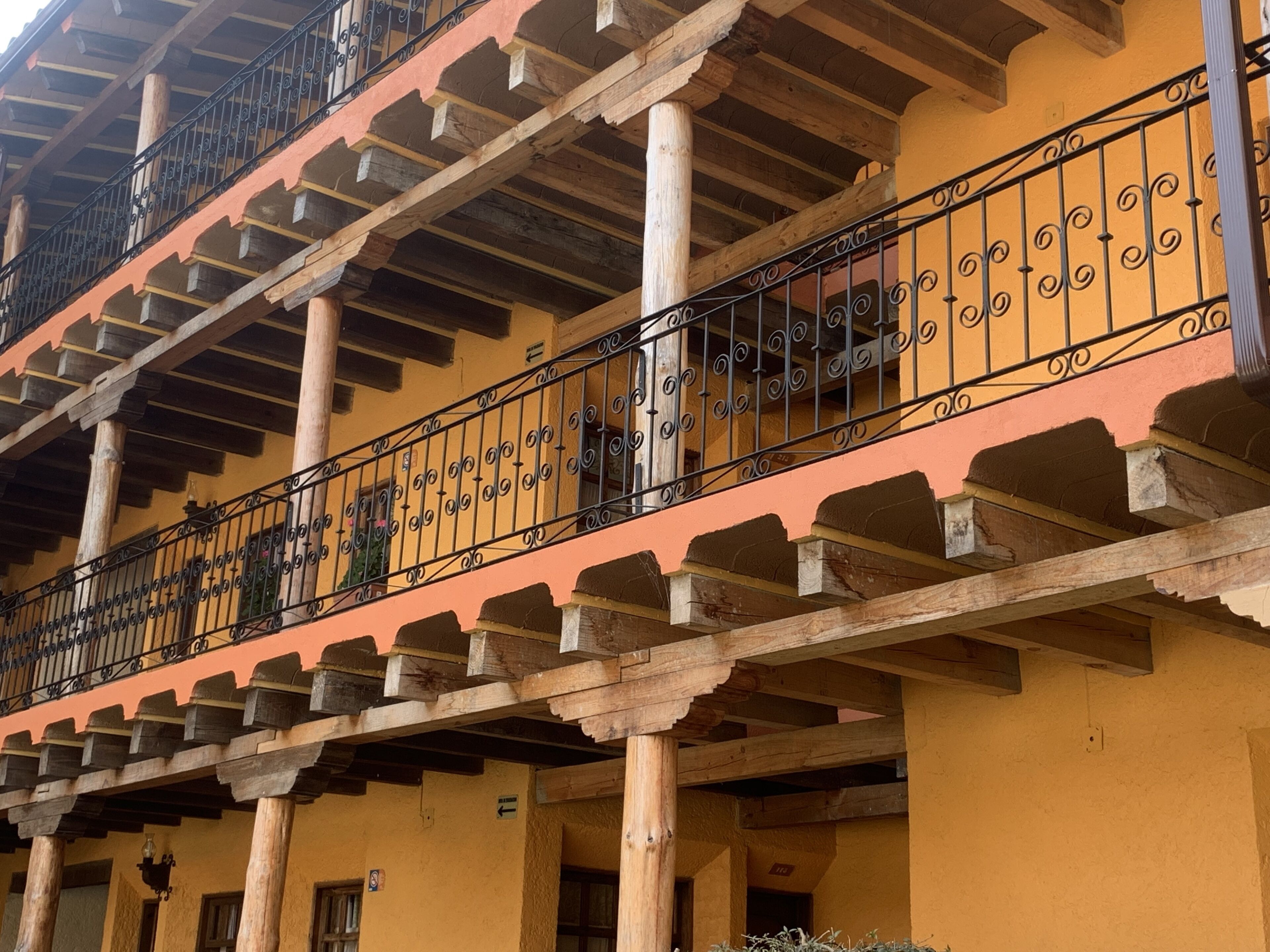 A multi-story building with balconies featuring wrought iron railings and wooden beams.