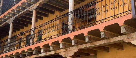 A multi-story building with balconies featuring wrought iron railings and wooden beams.