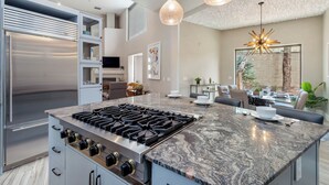 A modern kitchen with a large island, stainless steel appliances, and pendant lighting.