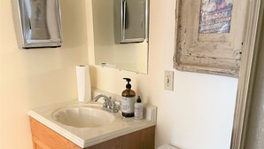 A bathroom with a wooden vanity, a sink, a mirror, and a toilet. - Former Art Gallery is now spacious lodging (Sedan)