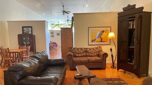 A living room with a leather couch, a patterned sofa, a wooden coffee table, and a cabinet with books. - Former Art Gallery is now spacious lodging (Sedan)