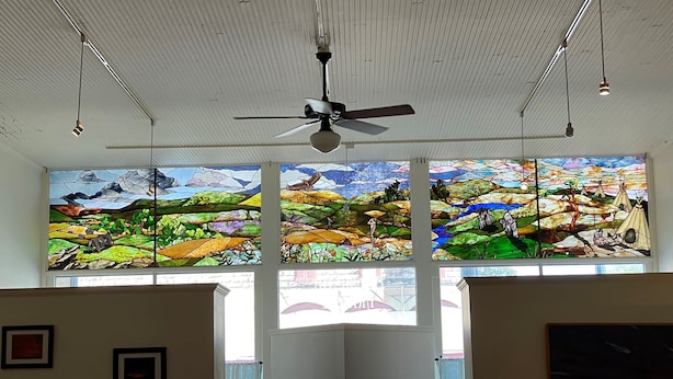 A room with a ceiling fan, large stained glass windows, and framed pictures on the walls. - Former Art Gallery is now spacious lodging (Sedan)
