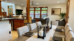 Una sala de estar moderna con comedor, muebles de madera y ventanas amplias.