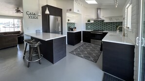 Une cuisine moderne dotée d’un îlot central, de meubles de couleur noire et d’appareils électroménagers en acier inoxydable.