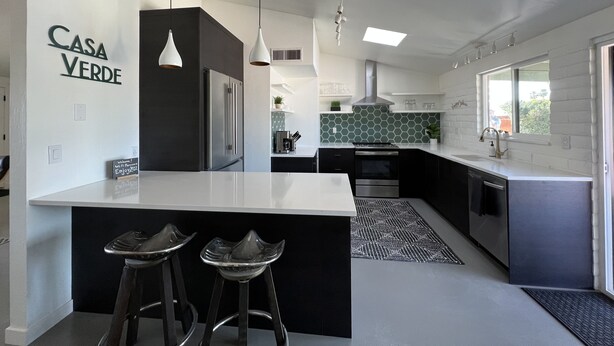 Une cuisine moderne dotée d’un grand îlot central, de meubles de rangement aux couleurs sombres et d’un pare-feu en carreaux hexagonaux.