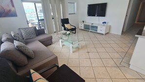 A modern living room with a sofa, coffee table, and a TV mounted on the wall. - Cranbourne Court Beach Side Apartments (Maroochydore)