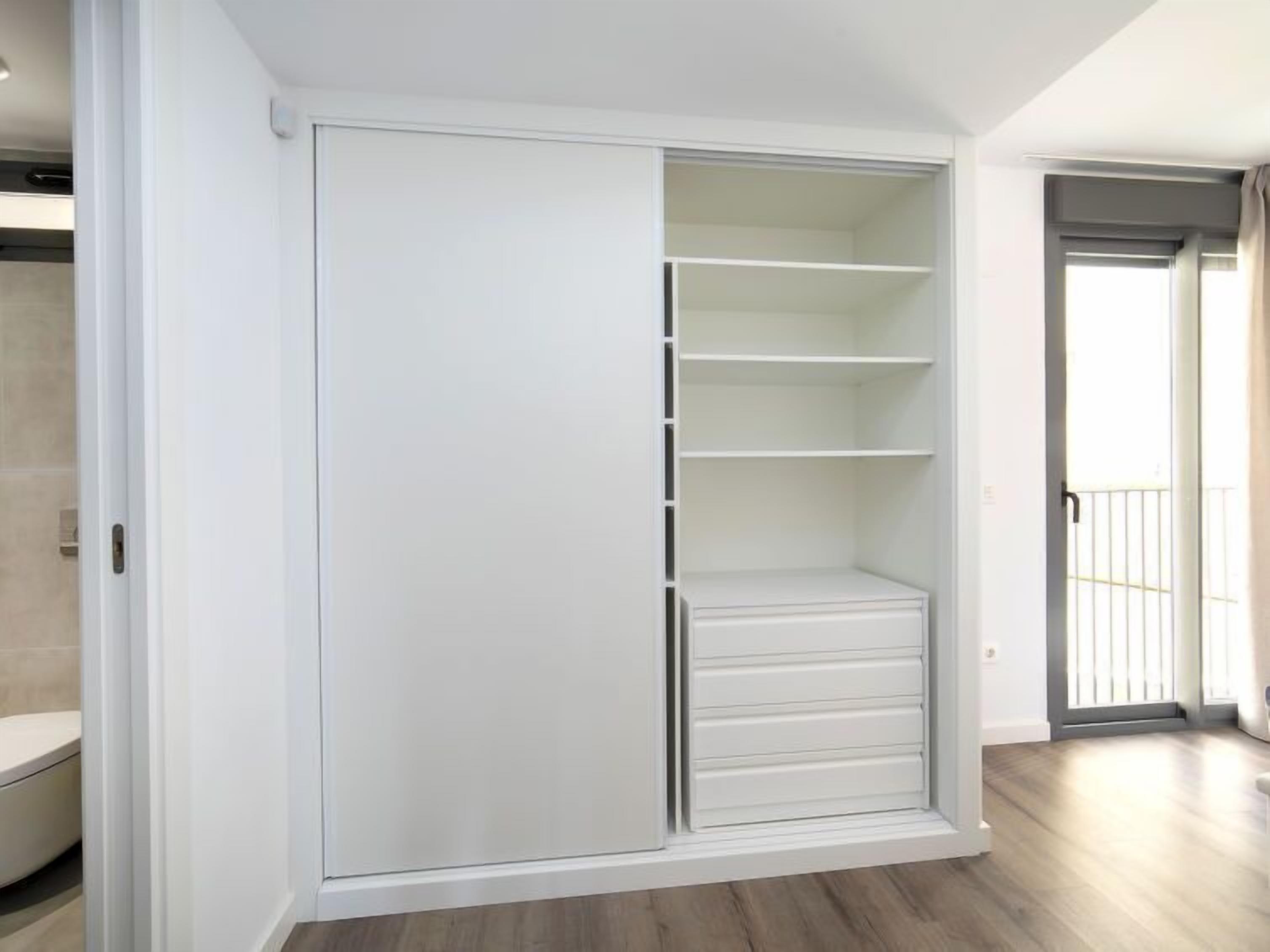 A modern closet with sliding doors, multiple shelves, and a built-in drawer unit.