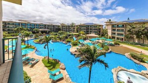 Un resort con varias piscinas, palmeras y un cielo azul despejado.