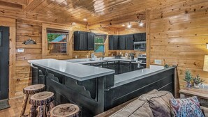 L’intérieur d’un chalet en bois comprend un îlot de cuisine, des meubles de cuisine noirs et un coin salon confortable.