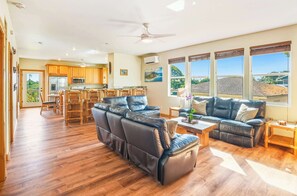 A spacious living area with a leather sofa, a dining table, and a kitchen in the background.