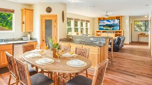 A spacious kitchen with wooden cabinets, a dining table set for four, and a large island. - 10 Bedroom Sleeps 24 w/ AC - Less than a 1 Minute Walk with views of Poipu Beach (Koloa)