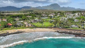 Un pueblo costero con playa, casas y montañas al fondo.