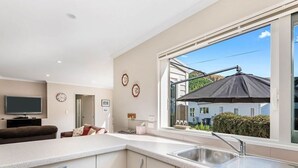 A modern kitchen with a large window, a built-in dishwasher, and a flat-screen TV. - Denbigh Escape - Perfect location, family-friendly! (Arrowtown)