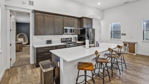 Een moderne keuken met een centraal eiland, barkrukken en uitzicht op de woonkamer.