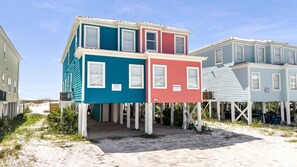 A beachfront property with a two-story house featuring a balcony and a covered porch.