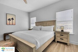 A bedroom with a large bed, two nightstands, a wooden headboard, and a window with blinds.