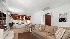 Sala de estar com sofá, mesa de centro e cozinha ao fundo.