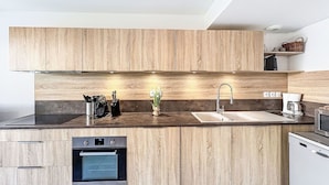 Una cocina moderna con armarios de madera, un horno de acero inoxidable, un lavamanos y una cafetera.
