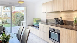 Una cocina moderna con armarios de madera, horno empotrado y un comedor con sillas y mesa.