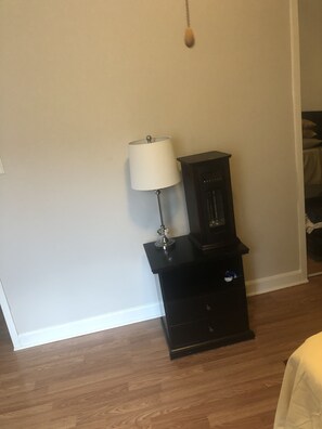 A cozy space with a wooden floor, featuring a cabinet with a lamp and a small drawer.
