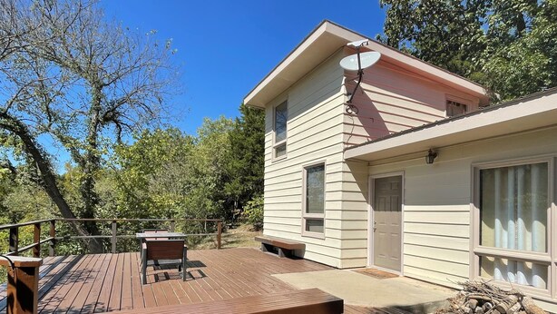 Une maison à deux étages dotée d’une terrasse, d’une antenne parabolique et d’une cour dallée de pierres.